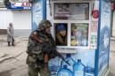 A pro-Russian rebel takes cover as a woman from inside a kiosk looks on, during what the rebels said was an anti-terrorist drill in Donetsk